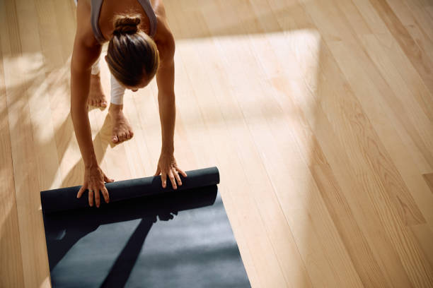 istock Above view of woman unrolling exercise mat while preparing to workout in Yoga studio. 2170530901