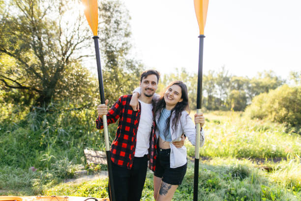 A happy couple stands together, radiating joy and satisfaction after an exhilarating kayaking trip. Their relaxed expressions reflect the thrill of their shared adventure, embodying a sense of accomplishment and togetherness in the great outdoors