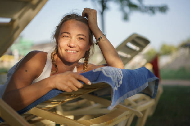 Happy blonde woman lying on a deckchair by the pool