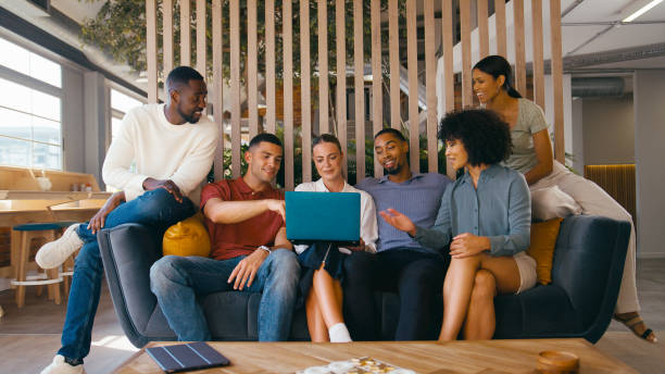 istock Multi-Cultural Business Team Sitting On Couch In Modern Open Plan Office Working On Laptop Together 2170539440