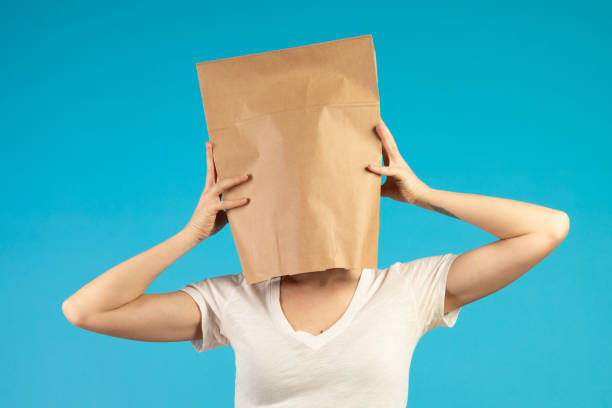 The woman is trying to remove the paper bag from her head.