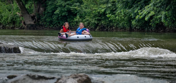 Two girls enjoy a ride in an inner tube down a drop in the Illinois River near Siloam Springs, Arkansas.