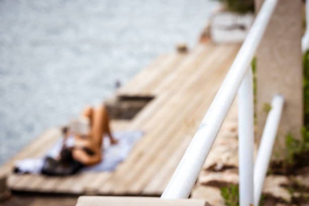 A scenic view of a rustic stone pathway descending towards the ocean, featuring steps and handrails on a rocky coast.