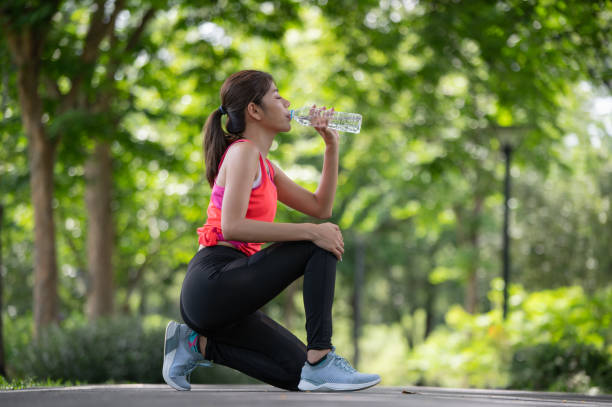 istock Attractive young runner woman drinking water on road when she finished running training 2170554475