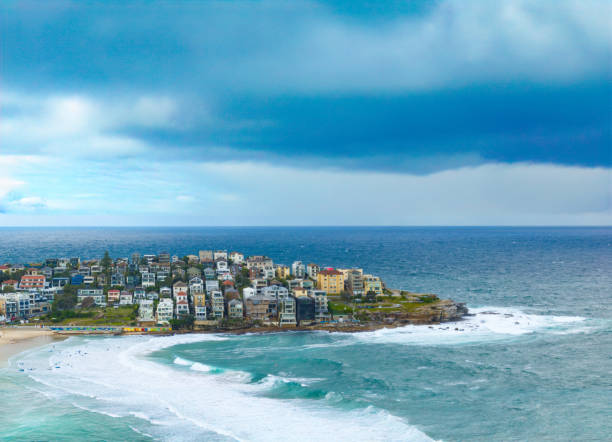 Capture the essence of summer with an aerial view of people relaxing on Bondi Beach, Sydney, under a dramatic afternoon sky, enjoying the sun and surf.