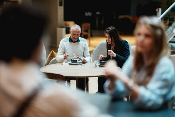 Two colleagues eating in a restaurant Two colleagues eating in a restaurant in a office building in Paris France french cafe interior stock pictures, royalty-free photos & images