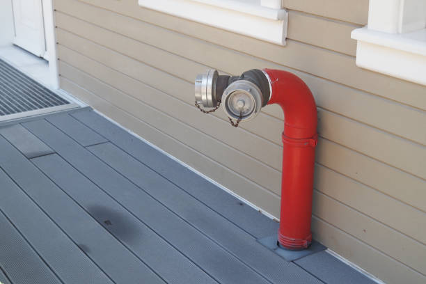 A strikingly bright red fire hydrant fitting is mounted beside a beautifully crafted wooden deck