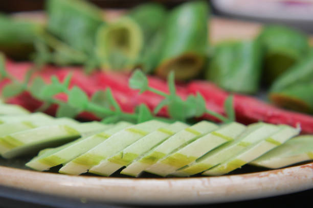 Vibrant vegetable platter featuring sliced greens and reds garnished with herbs.