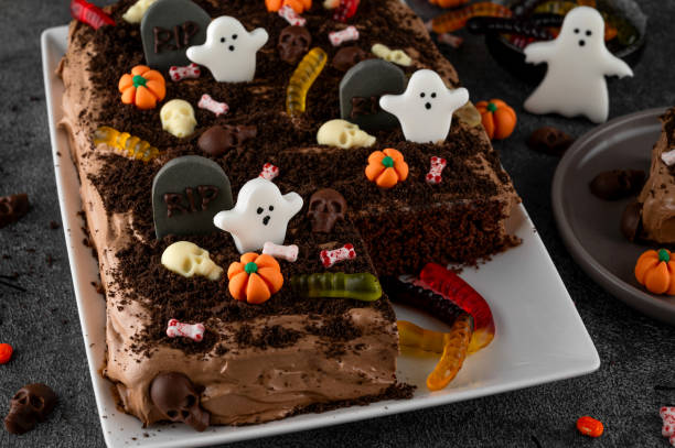 Halloween chocolate cake. Dirty cake with chocolate cream, decorated with worms, skulls, ghosts, pumpkins and sugar sprinkles on a dark background.
