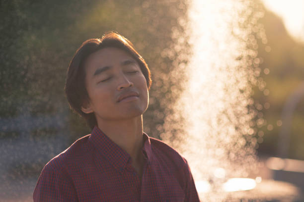 A man enjoying a peaceful moment on a sunny morning in the park next to a fountain.