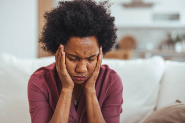 istock Stressed Woman Sitting on Sofa Holding Her Head 2170566823