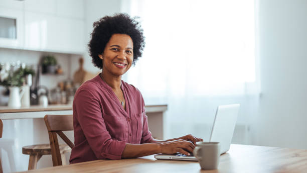 istock Smiling Woman Working on Laptop in a Bright Kitchen 2170566852