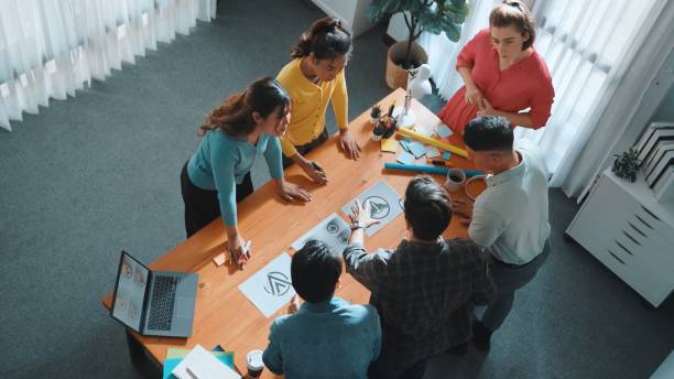 istock Top view of skilled designer holding logo while discussing with team. Symposium. 2170568344