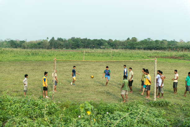 Assam, India-August 06, 2020: Group of men playing football in an open green field.