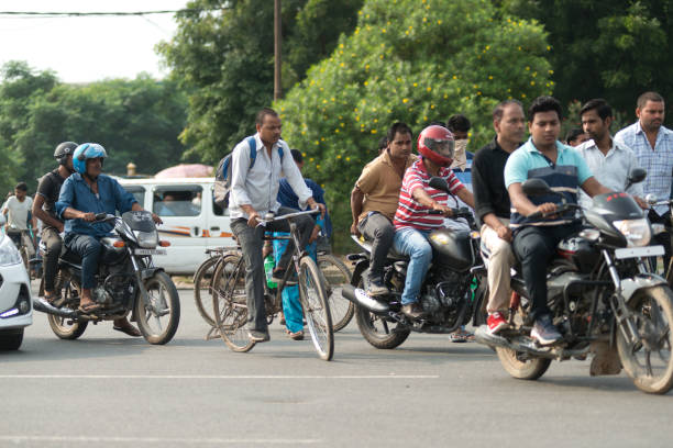 New Delhi, India - August 21, 2022: Stock photo showing person riding motorcycle on Indian main road with black and white striped concrete safety barrier.