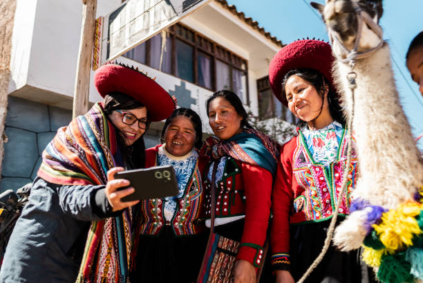 fotografii de stoc, fotografii și imagini scutite de redevențe cu turist care arată telefonul mobil indigenului chinchero din districtul chinchero, peru - chinchero district