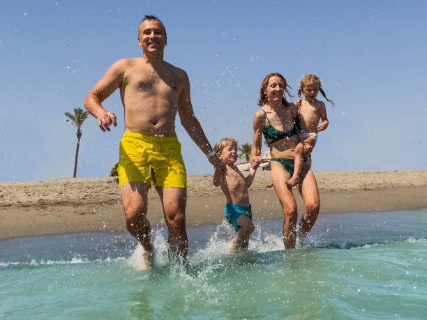 istock Two grown-ups and kids create splashes at warm sea hold hands 2170577511