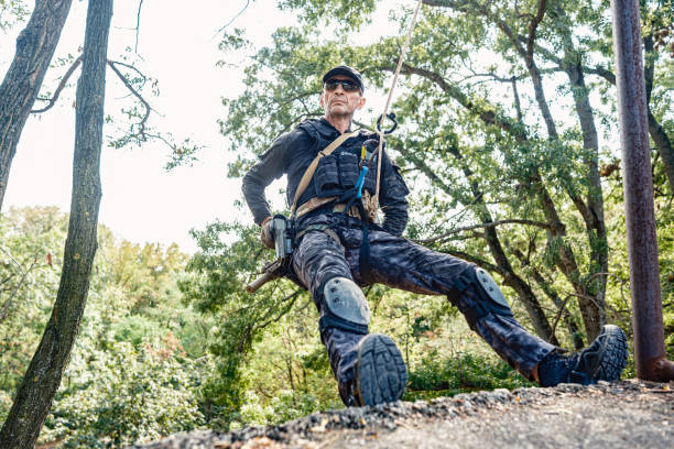 Athletic man working out and climbing a rope, during obstacle course in boot camp