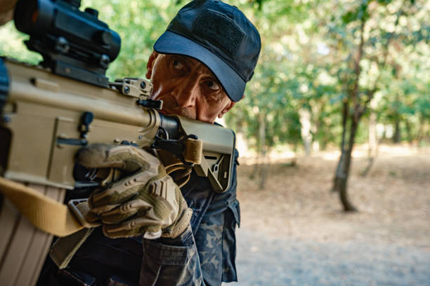 Military training: single soldier in black camouflage gear tactical move with rifle beside abandoned brick building, practising military discipline and teamwork during a close-quarters operation.