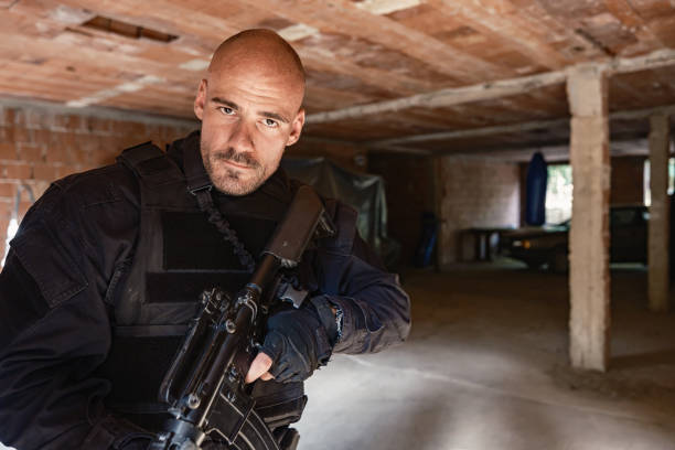 Military training: single soldier in black camouflage gear tactical move with rifle inside abandoned brick building, practising military discipline and teamwork during a close-quarters operation.