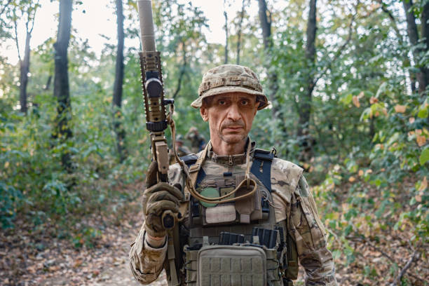 Military training: soldier in camouflage gear tactical move with rifle in wooded area during military training, practising military discipline and teamwork during outdoor operation.