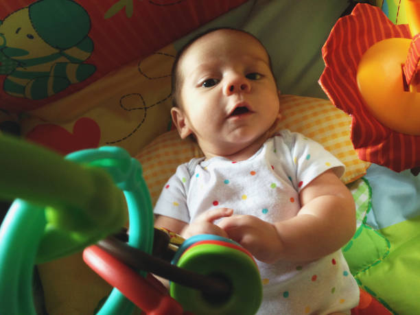 A baby boy lies happily on his play mat.