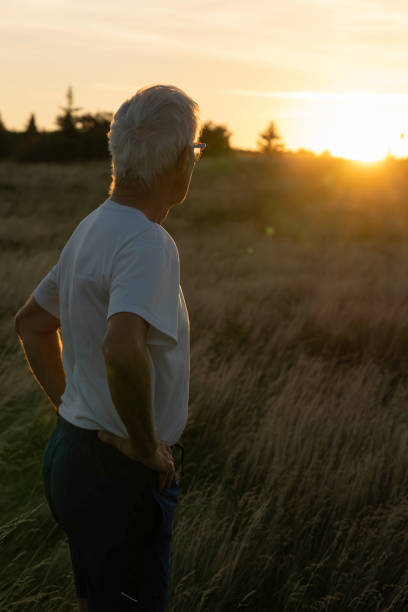 istock Senior man pauses in grasses at sunset 2170589844