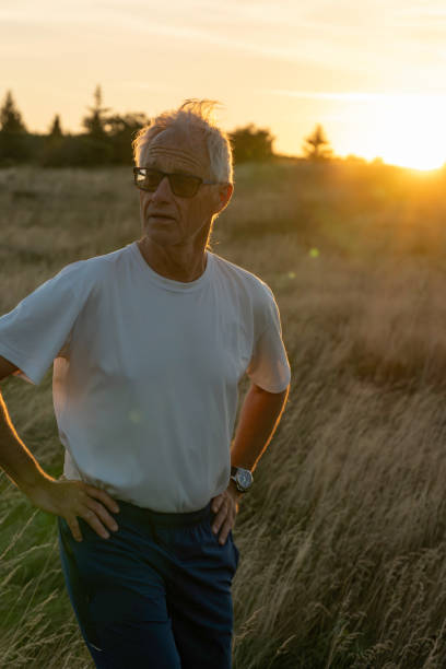 istock Senior man pauses in grasses at sunset 2170589846