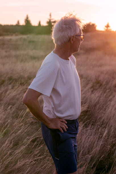 istock Senior man pauses in grasses at sunset 2170590466