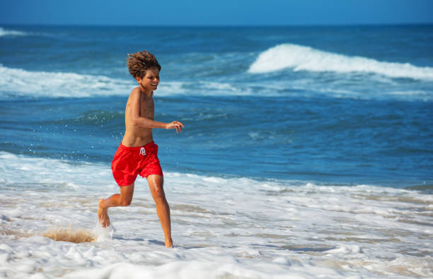 istock Smiling boy energetically play at the water edge on a bright day 2170591544
