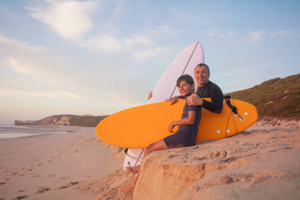 istock Father and son enjoying beach day with a surfboard at sunset 2170591595