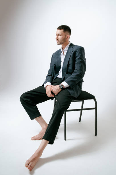 istock Handsome man, fashion model sits on chair, barefoot 2170592171