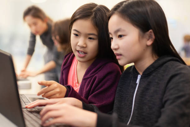 istock Two Asian Chinese girls students collaborate together using laptop computer in elementary school classroom 2170613413