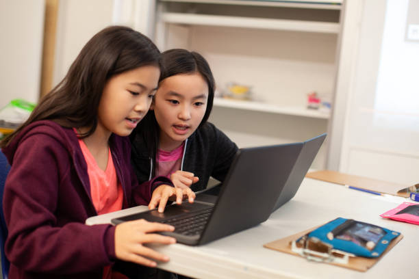 istock Two Asian Chinese girls students collaborate together using laptop computer in elementary school classroom 2170613515