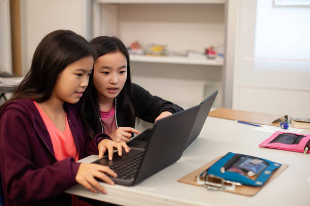 istock Two Asian Chinese girls students collaborate together using laptop computer in elementary school classroom 2170613551