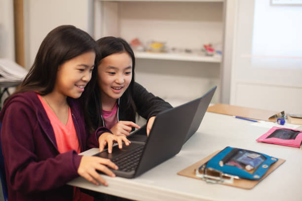 istock Two Asian Chinese girls students collaborate together using laptop computer in elementary school classroom 2170613577