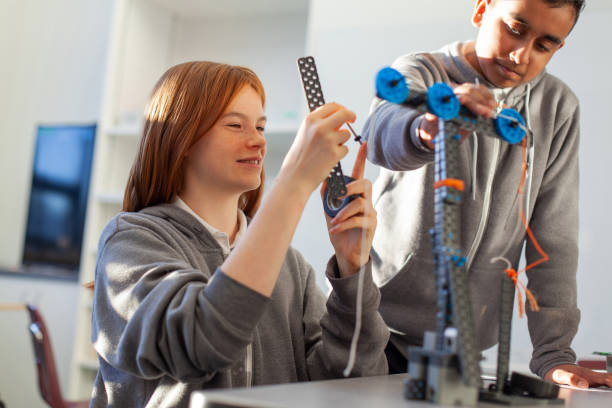 istock Teenage girl in high school classroom making physics construction science engineering technology mathematics STEM project with Asian classmate 2170615346