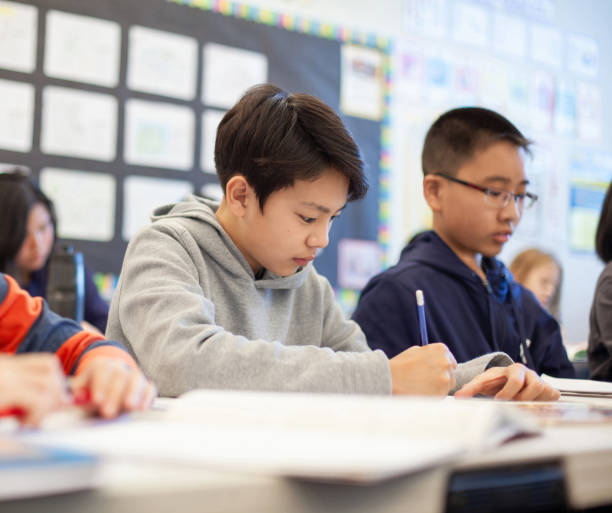 istock Asian multiracial Korean Japanese boy studies in elementary school classroom with classmates 2170615675