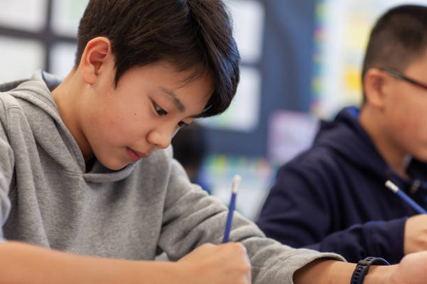 istock Asian multiracial Korean Japanese boy studies in elementary school classroom with classmates 2170615866