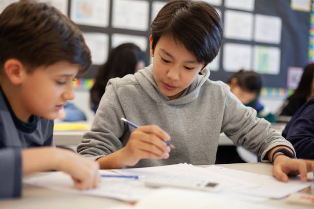 istock Asian multiracial Korean Japanese boy studies in elementary school classroom with classmate 2170615969