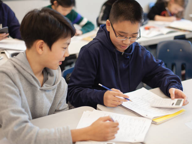 Asian Chinese boy studies in elementary school classroom with classmate