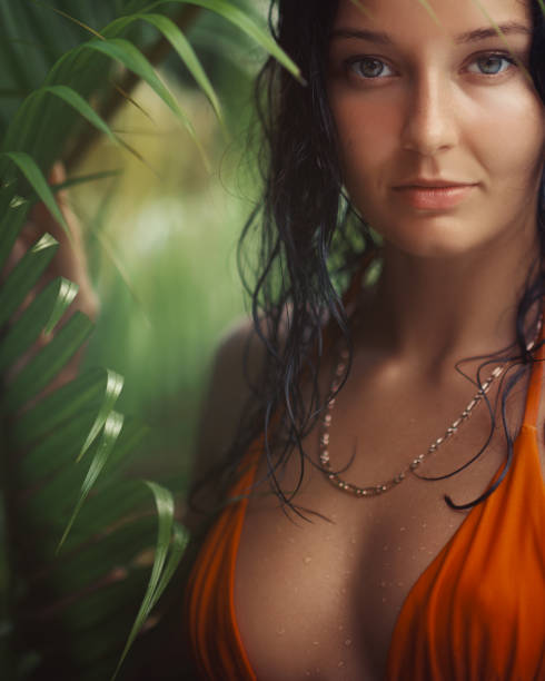 istock Sensual Brunette in Orange Bikini Surrounded by Lush Tropical Leaves 2170624703