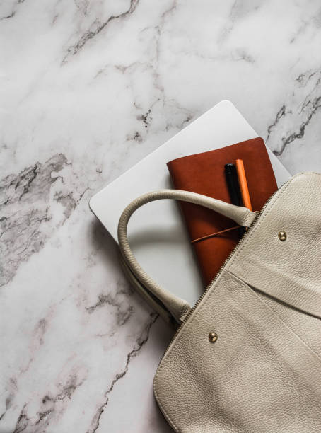 istock Women's beige leather bag, laptop, notebook, pen on marble background, top view 2170628119