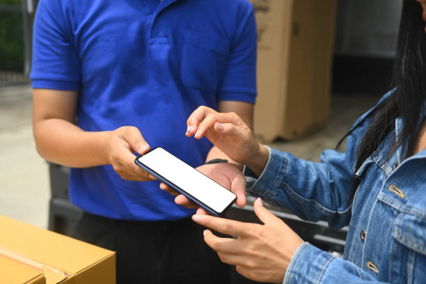 istock Young woman putting signature while receiving parcel box from delivery man 2170629084