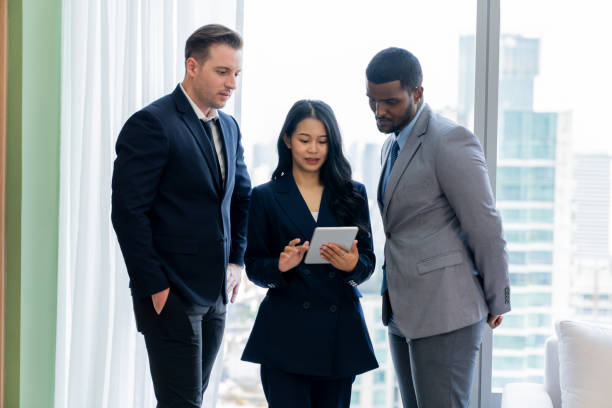 istock Diverse smart businesspeople standing near window with skyscraper. Ornamented.. 2170629743