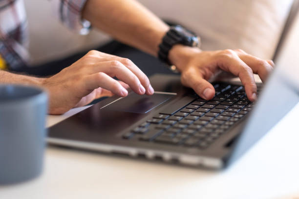 Close-up of unknown man's hands working on laptop in his office