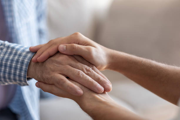 istock Close-up of young man's hands tenderly holding old man's hands 2170629861