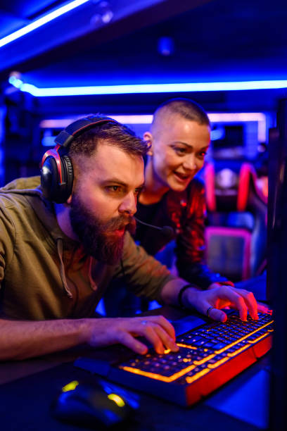istock Focused gamer with headset playing game in neon lit cybercafe. 2170631550