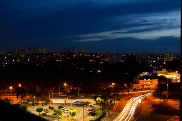 City at night, buildings and avenue lit up and sky with clouds. Car traffic.