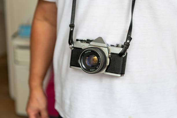 A person carrying a vintage SLR photography film camera.